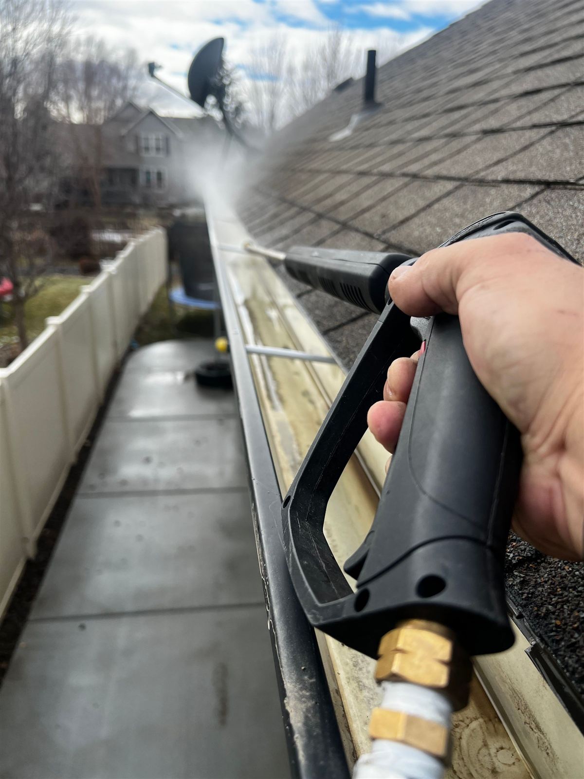 Close-up of a gutter cleaning wand during a pressure washing service — representative finish example